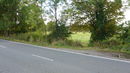View across the road at Harlow Common showing gap in hedgerow and continuation of footpath