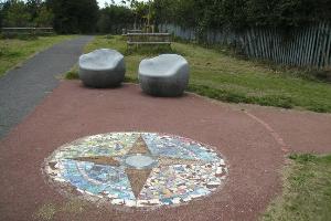 Ground mosaic and stone chairs at path junction, waypoint 2