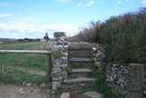 A stone stile with St Nectans church tower in the background. This form of stile is very common from here and down into Cornwall