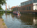 A modern narrow boat.
The canals are mainly used for pleasure now, but their original industrial purpose can be seen in the mills behind.
See also the footbridge (E).